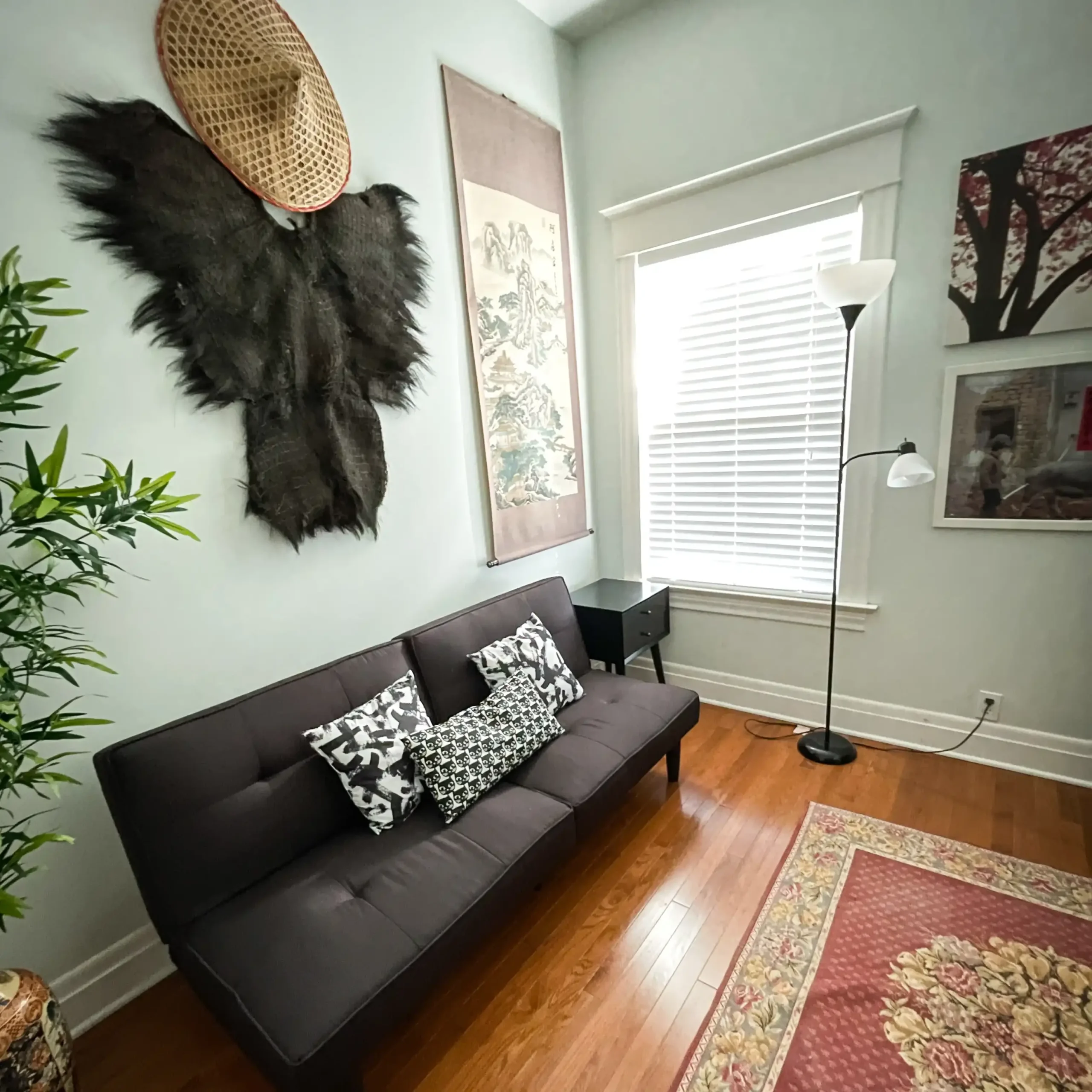 A traditional Chinese fisherman's coat and hat hang on the wall over a futon couch in the Far East room at the Hoover House.