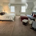 A California King sits across from a futon couch and two Ottomans.